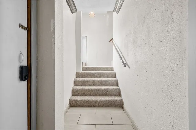 a view of staircase with white walls and white door