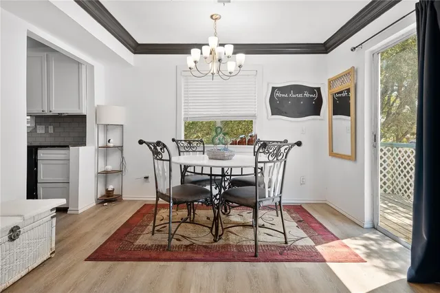 a dining room with wooden floor a chandelier a wooden table and chairs