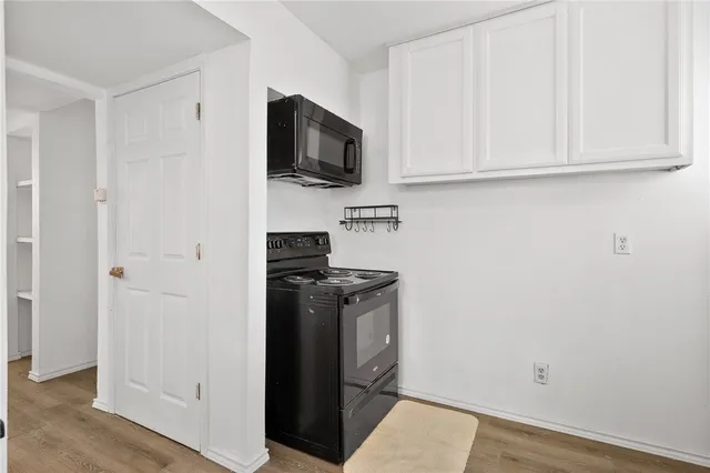 a view of a kitchen with stainless steel appliances wooden floor and cabinets