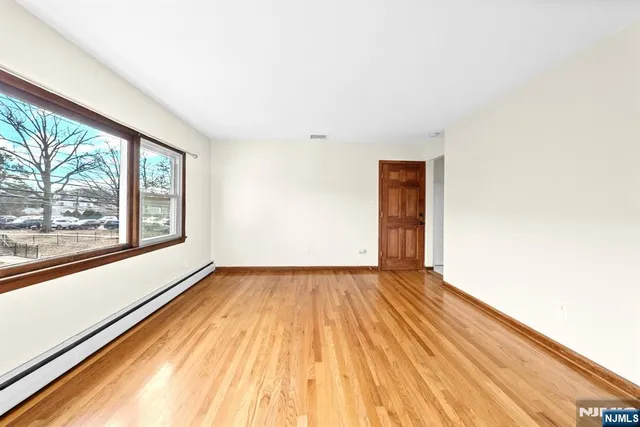a view of an empty room with a window and wooden floor