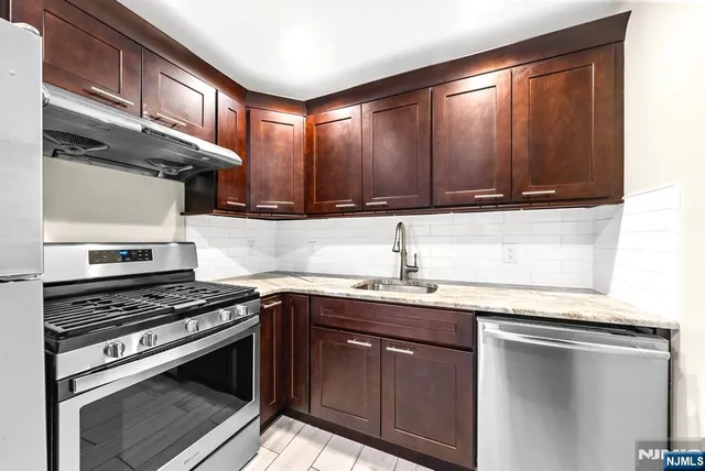 a kitchen with stainless steel appliances granite countertop a refrigerator and a sink