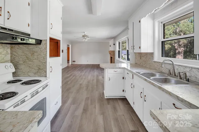 a kitchen with granite countertop a sink stove and cabinets