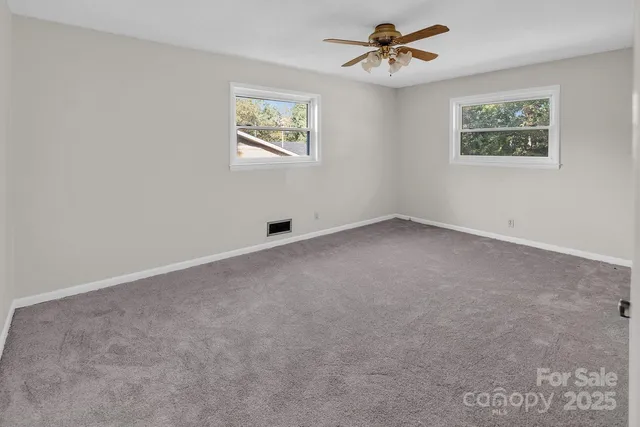 an empty room with windows and ceiling fan