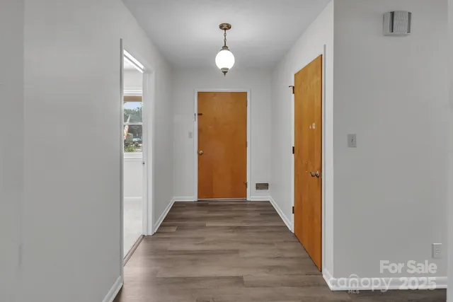 a view of a hallway with wooden floor and a chandelier