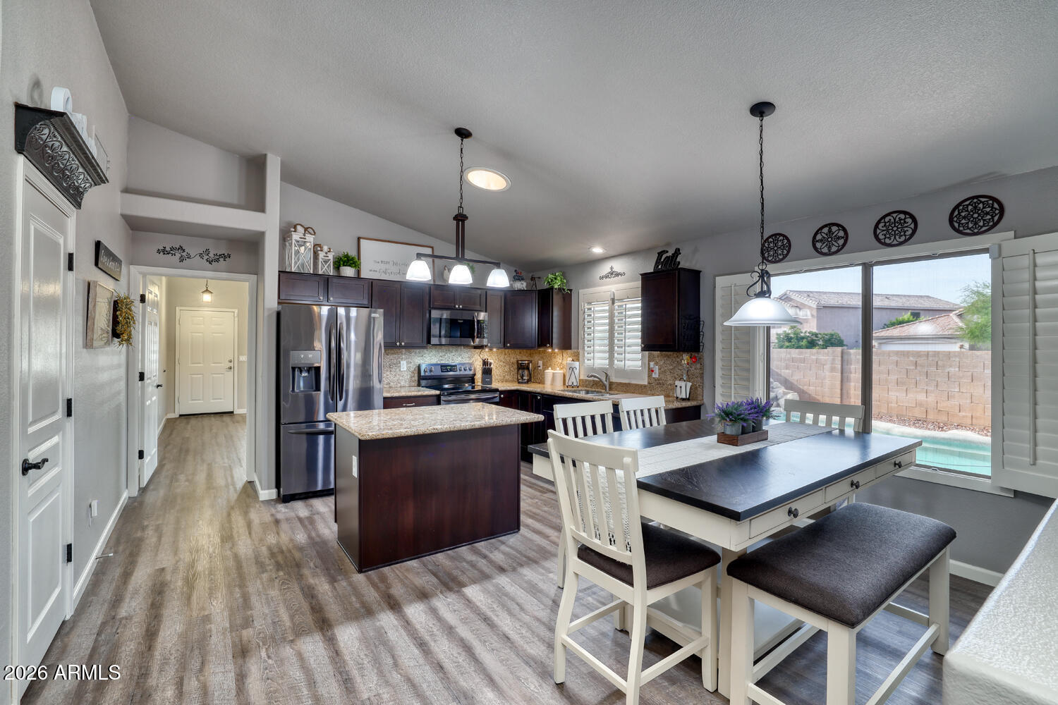 2206 East Ruby Lane Phoenix, AZ 85024 - Photo 7 of 29 a kitchen with stainless steel appliances kitchen island granite countertop a table chairs and a wooden floor