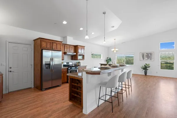 a kitchen with stainless steel appliances granite countertop a sink a stove a refrigerator and a dining table with wooden floor