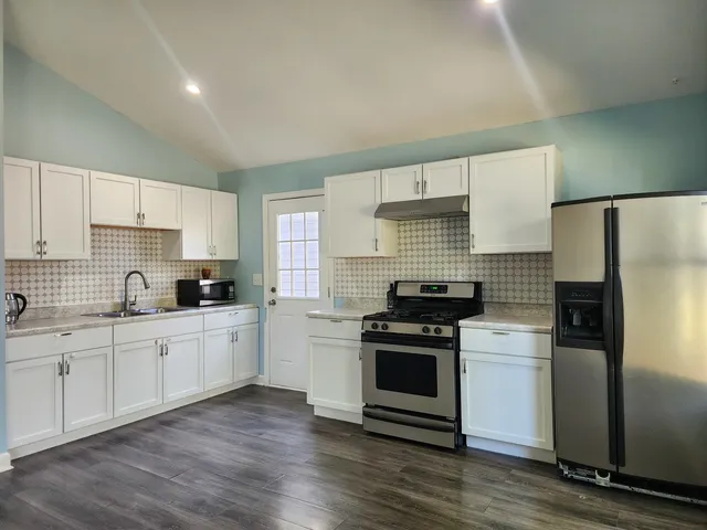a kitchen with granite countertop white cabinets and stainless steel appliances