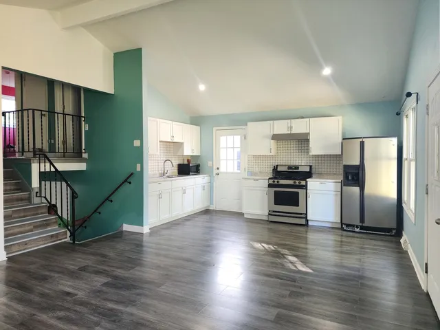 a kitchen with granite countertop a refrigerator and a stove top oven