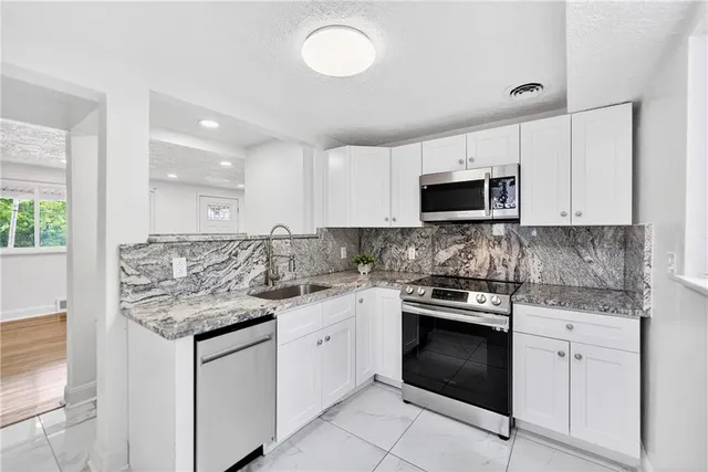a kitchen with stainless steel appliances granite countertop white cabinets granite counter tops and a stove