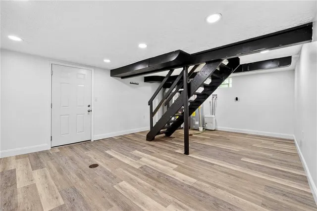 a view of an empty room with wooden floor and stairs