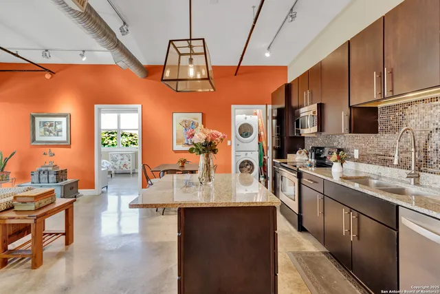 a large kitchen with stainless steel appliances granite countertop a sink dishwasher stove refrigerator and cabinets