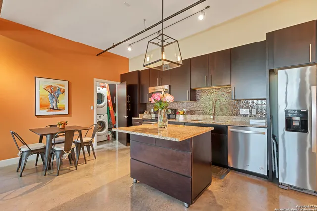 a kitchen with stainless steel appliances granite countertop a sink a stove and a refrigerator