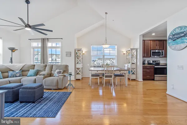 a living room with furniture kitchen view and a wooden floor