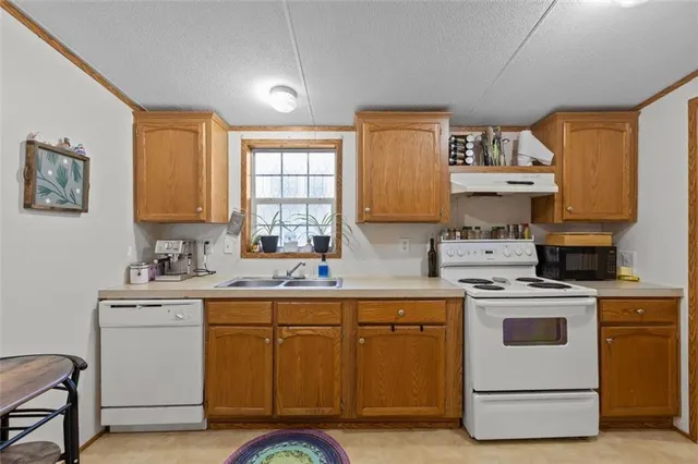 a kitchen with a stove a sink and white cabinets with wooden floor