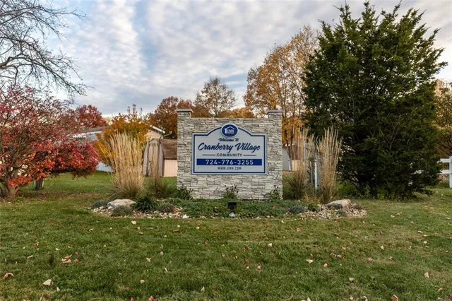 a sign of golf club on a wall under a tree