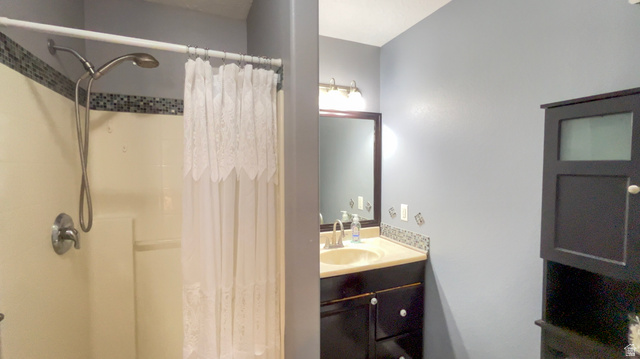 1797 Sunset Road Enoch, UT 84721 - Photo 25 of 80 Bathroom featuring a shower with mosaic tile accent, single vanity with a light-colored countertop, dark wood-finish cabinetry, and a mirrored medicine cabinet