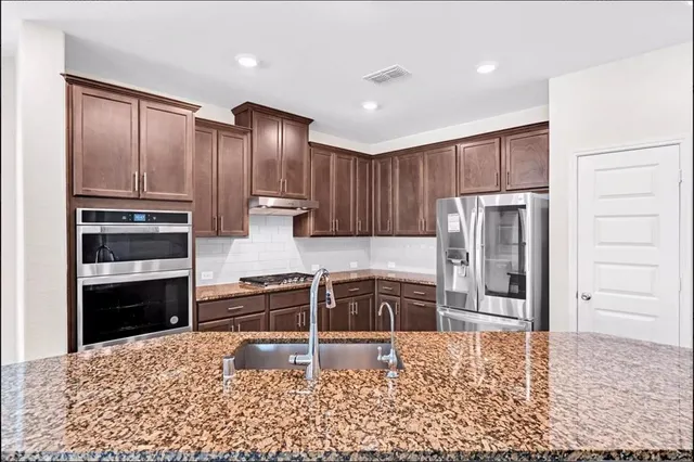 a kitchen with granite countertop wooden cabinets and refrigerator