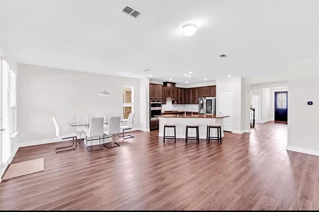 a living room with furniture and a dining table with kitchen appliances