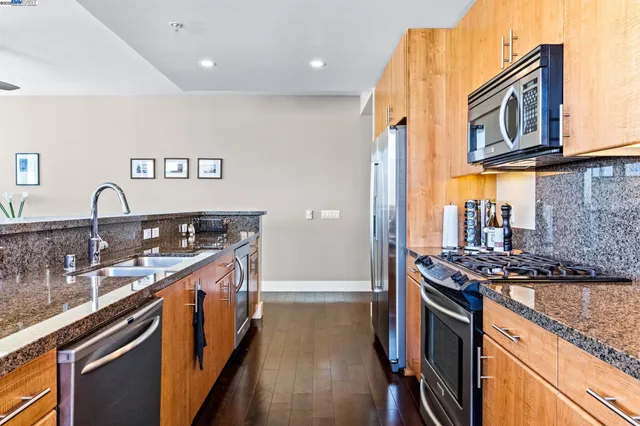 a kitchen with stainless steel appliances granite countertop a refrigerator a stove and a sink