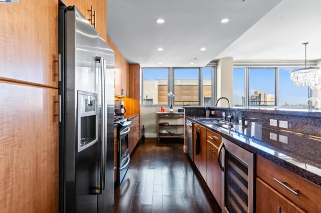 a kitchen with stainless steel appliances granite countertop a refrigerator a sink dishwasher a stove and white countertops with wooden floor