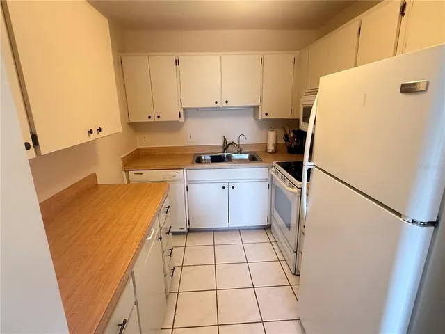 a kitchen with a sink a stove a refrigerator and white cabinets