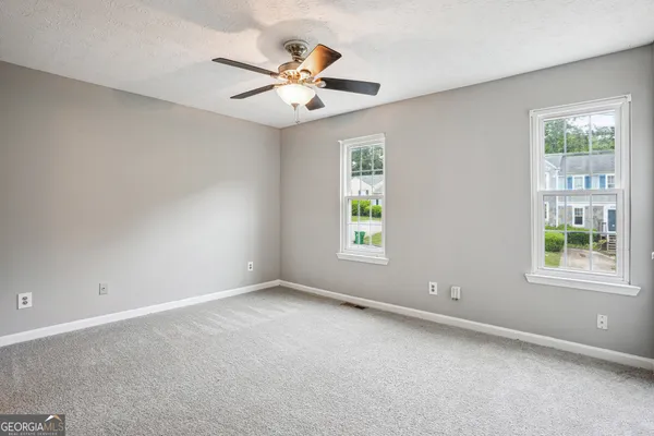 an empty room with windows and fan