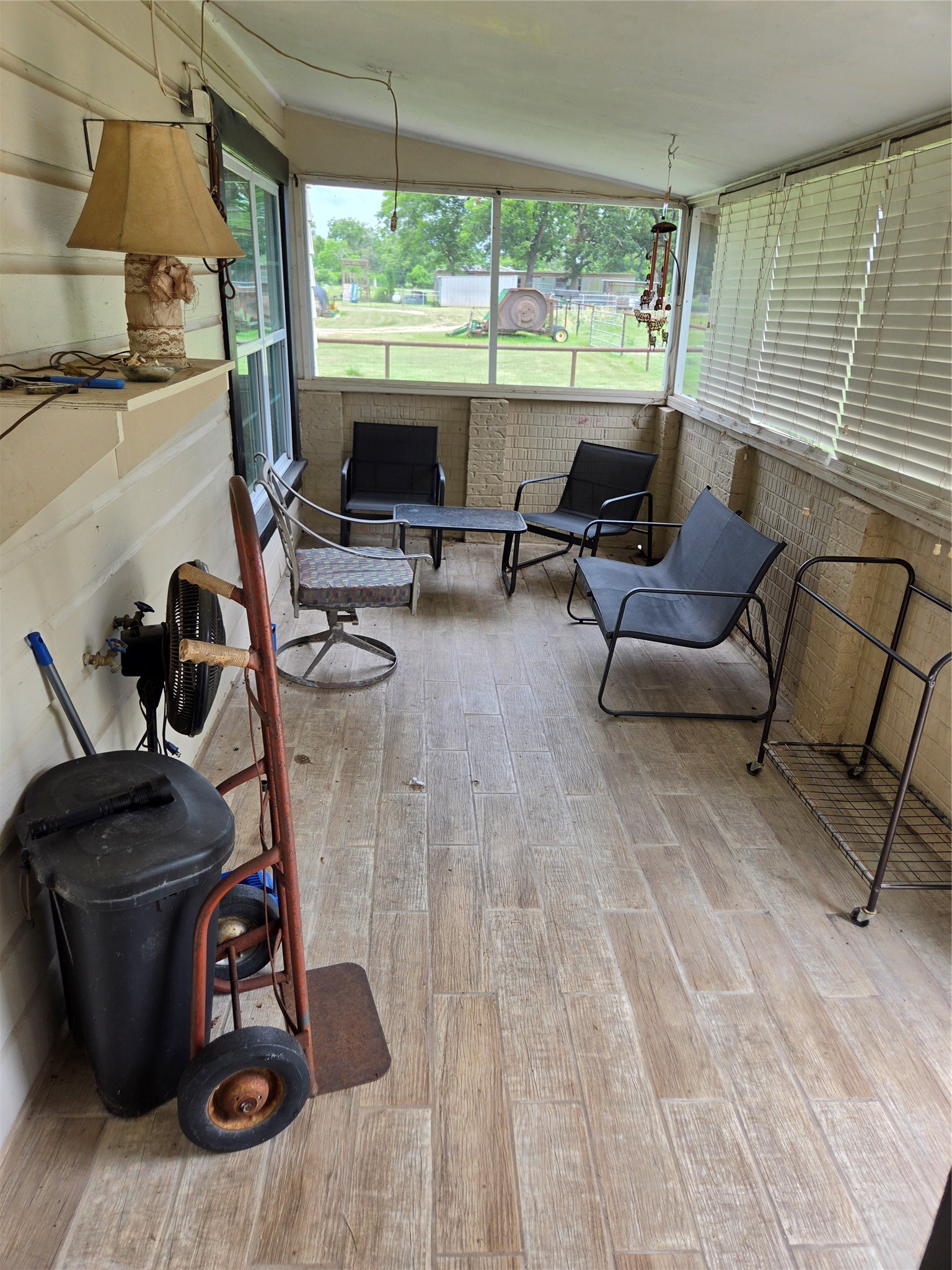 4910 FM 3012 Road Wharton, TX 77488 - Photo 19 of 21 This enclosed porch features tiled flooring, large windows with blinds, and casual seating, offering a cozy space with views of the backyard.