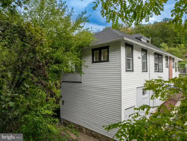 an empty room with wooden floor fireplace and windows