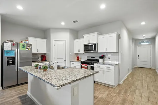 a kitchen with stainless steel appliances granite countertop a sink dishwasher stove top oven and refrigerator