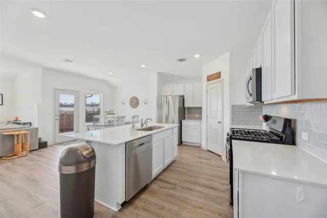 a large kitchen with stainless steel appliances granite countertop a lot of counter space and wooden floor