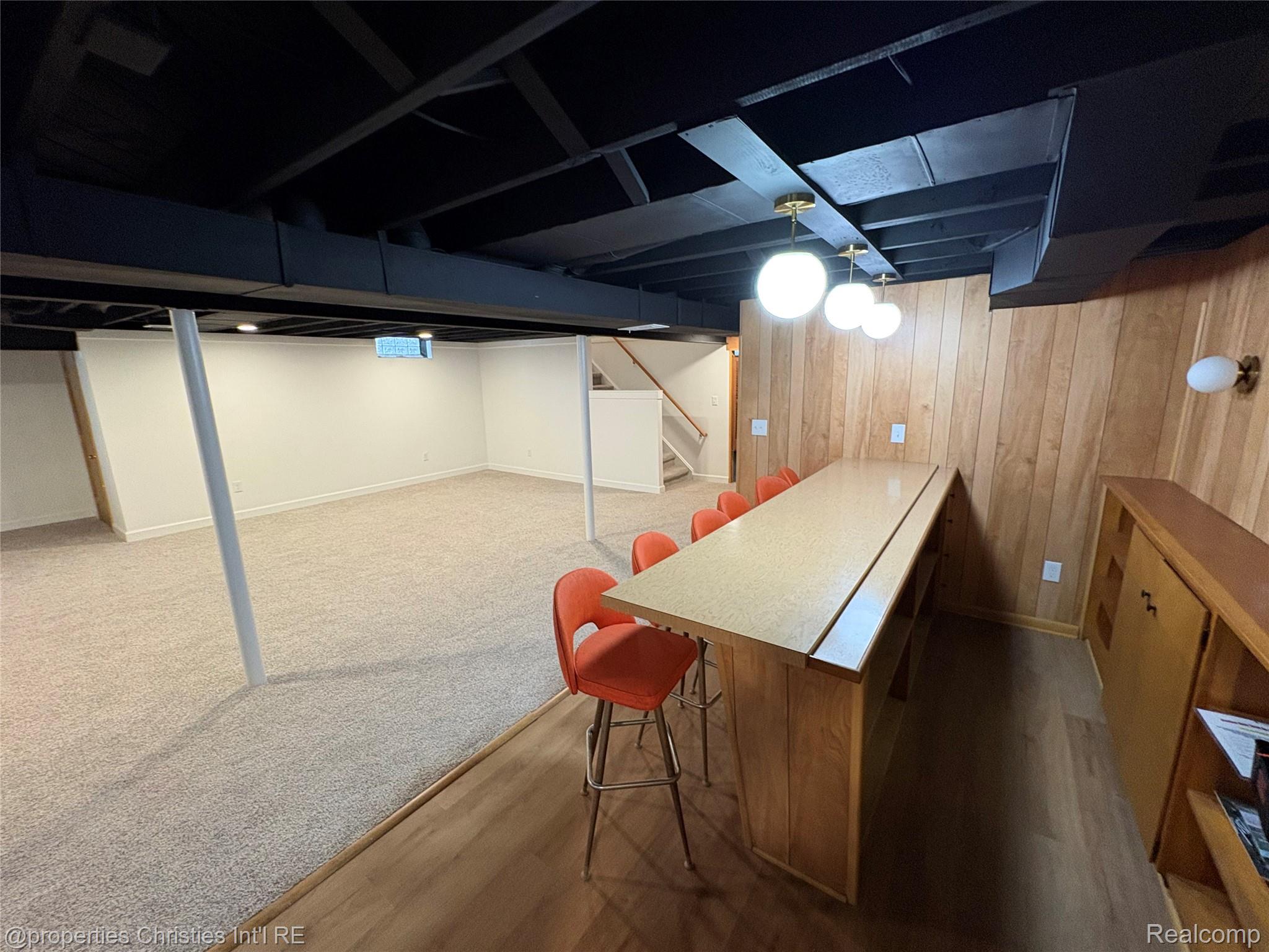 17330 Beverly Road Franklin, MI 48025 - Photo 20 of 24 Finished basement with dark wood-style flooring, wooden walls, and a bar