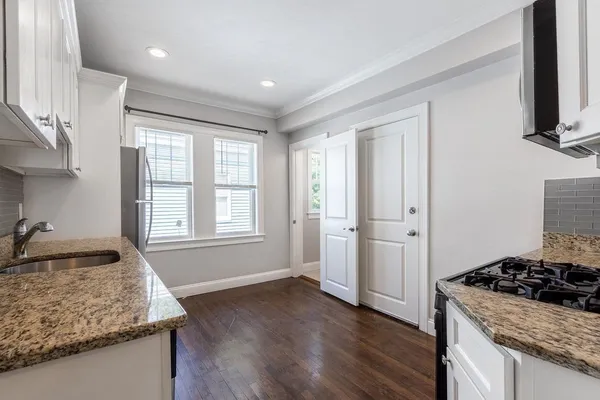 a kitchen with granite countertop a sink stove and cabinets