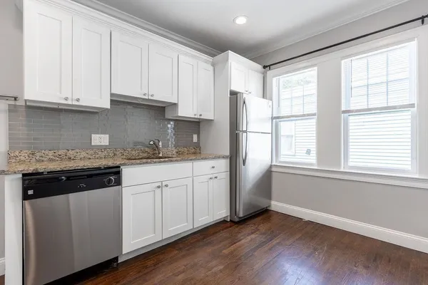 a kitchen with granite countertop white cabinets and a window