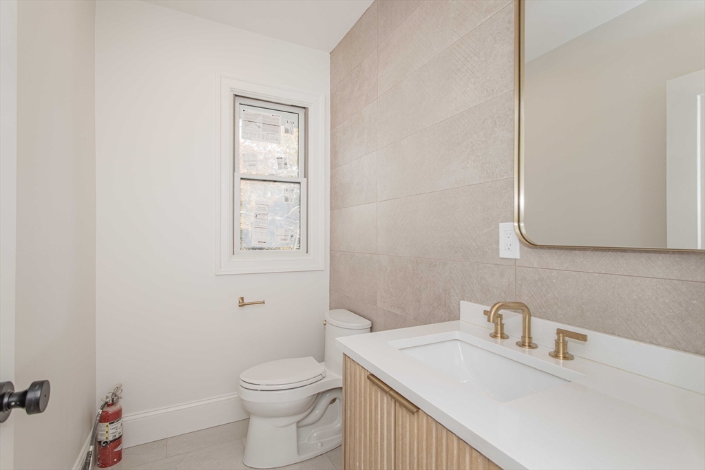 125 Mt Vernon Street, Unit 2 Newton, MA 02465 - Photo 21 of 36 a bathroom with a toilet sink vanity and mirror
