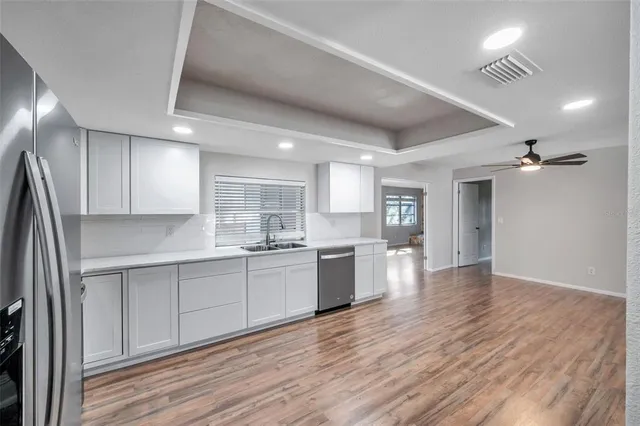a large kitchen with cabinets wooden floor and stainless steel appliances