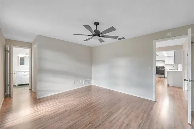 a view of empty room with wooden floor and a ceiling fan