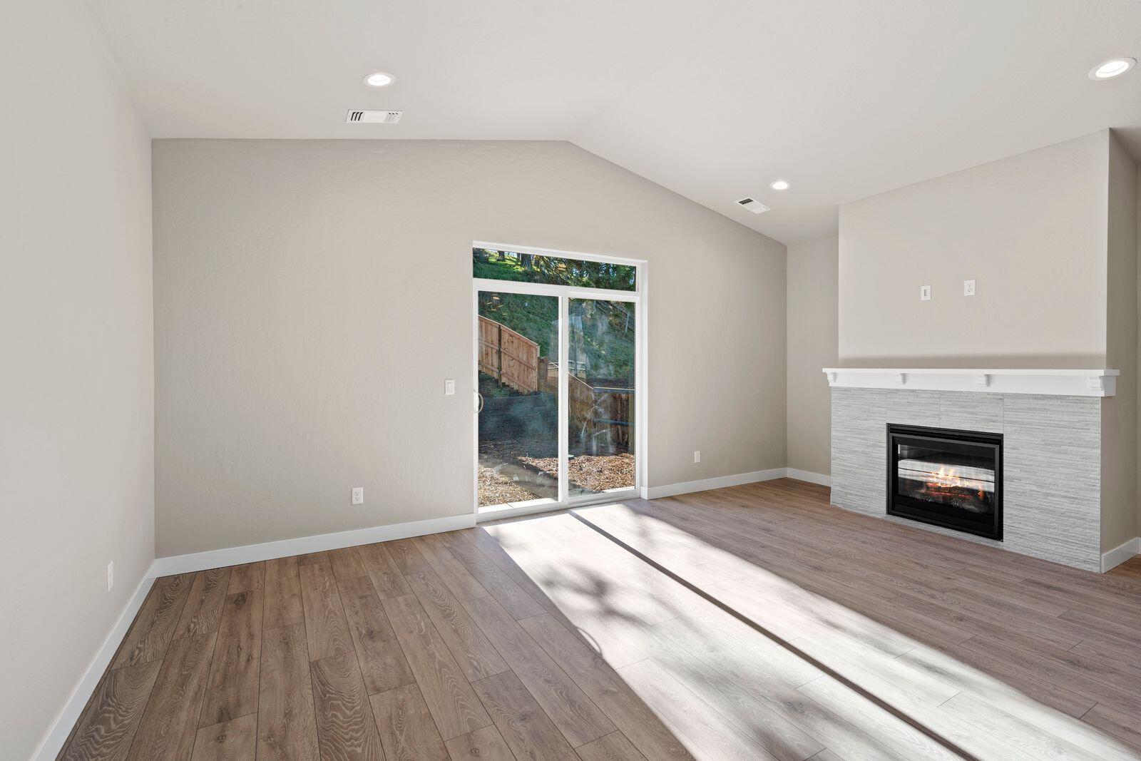1135 Pumpkin Ridge, Unit 319 Eagle Point, OR 97524 - Photo 13 of 34 an empty room with wooden floor fireplace and windows