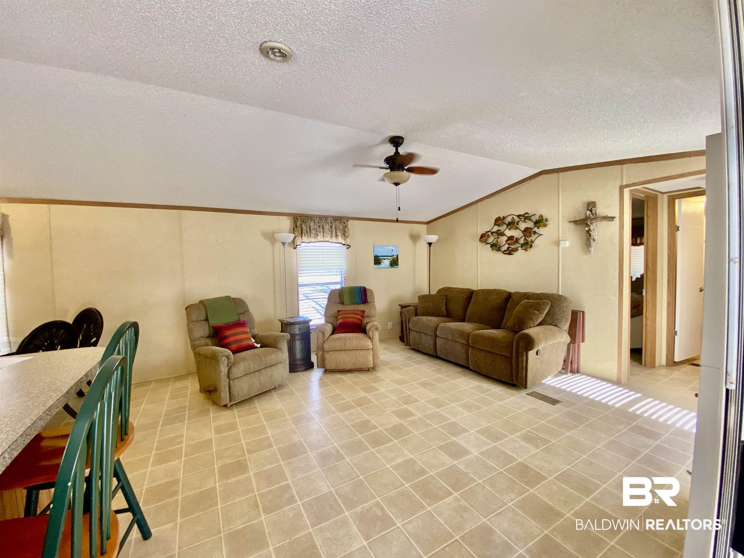294 Eureka Way Uriah, AL 36480 - Photo 5 of 18 Living room with light tile patterned floors, lofted ceiling, ornamental molding, a ceiling fan, and a textured ceiling