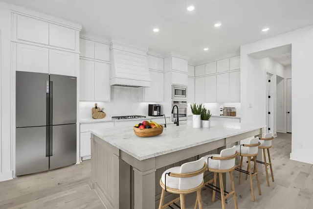 a kitchen with stainless steel appliances a white table and chairs in it