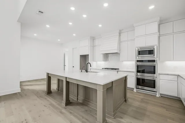 a kitchen with a sink stainless steel appliances and white cabinets