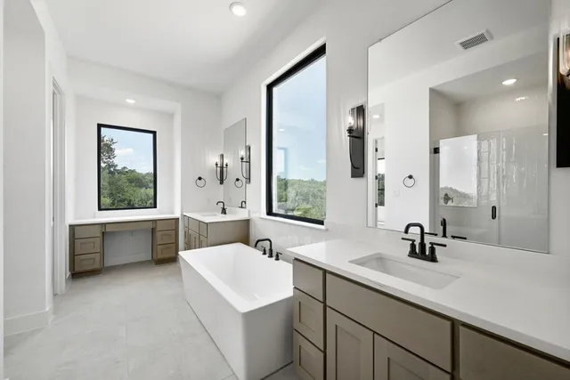 a bathroom with a double vanity sink large mirror and a bathtub