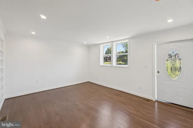 an empty room with wooden floor and window
