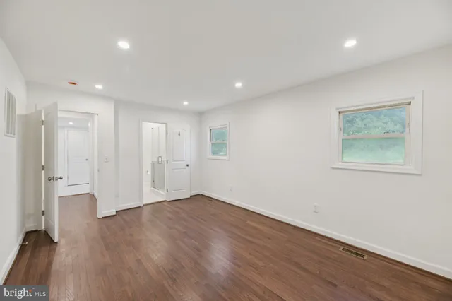 a view of an empty room with wooden floor and closet
