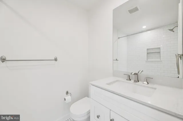 a bathroom with a white sink a toilet and a mirror