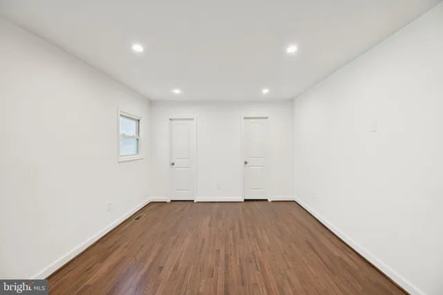 a view of an empty room with wooden floor and stairs