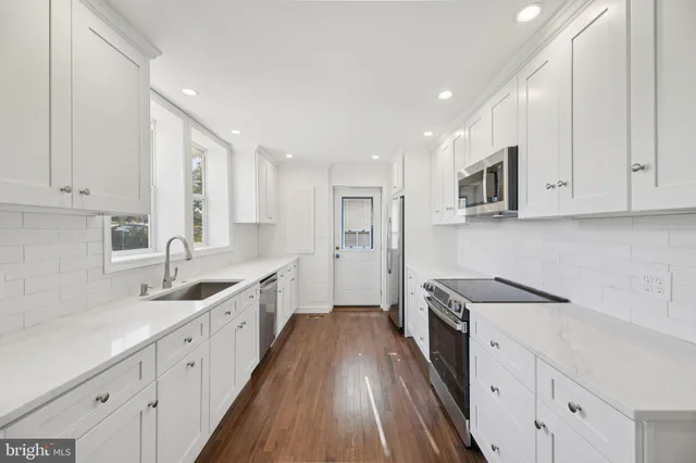 a kitchen with granite countertop white cabinets and stainless steel appliances