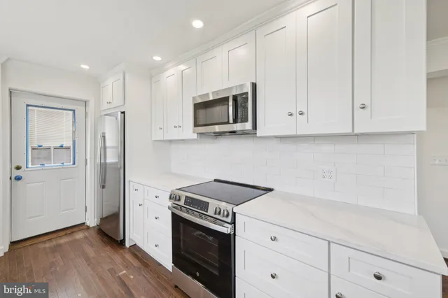 a kitchen with stainless steel appliances granite countertop white cabinets and a stove top oven