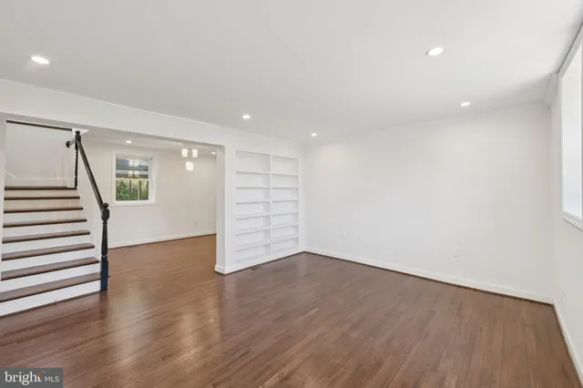 a view of an empty room with wooden floor and stairs