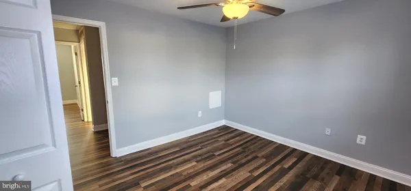 a view of an empty room with wooden floor and closet