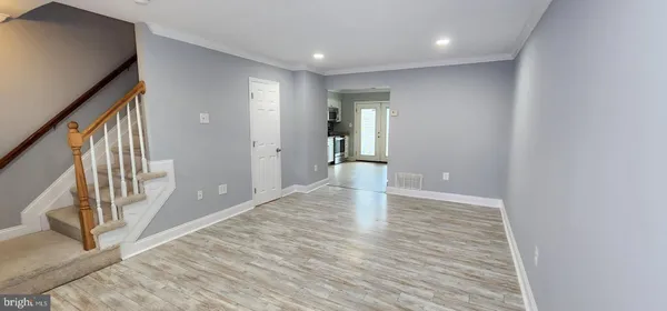 a view of an empty room with wooden floor and stairs